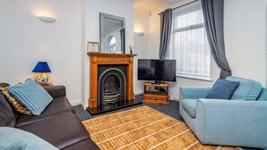 A living room with a fireplace, a television, a sofa, and a window with curtains. - Beeston Central House - near shops and University (Beeston)