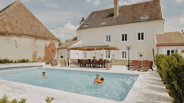 En swimmingpool med liggestole og en overdækket terrasse.