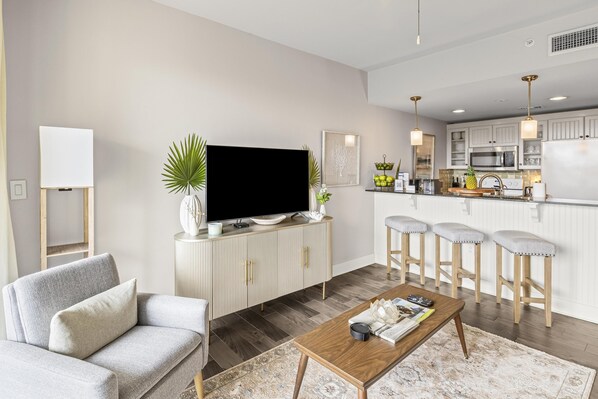 Una sala de estar moderna con un sofá, una mesa de centro y un televisor sobre un mueble.