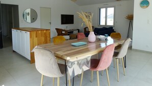 A modern kitchen with wooden beams, a dining area with a wooden table and chairs, and a living room with a sofa and TV. - House 6 with heated pool in St-Hilaire (Saint-Hilaire-de-Riez)