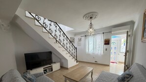 Een woonkamer met een trap, een televisie en een eethoek.