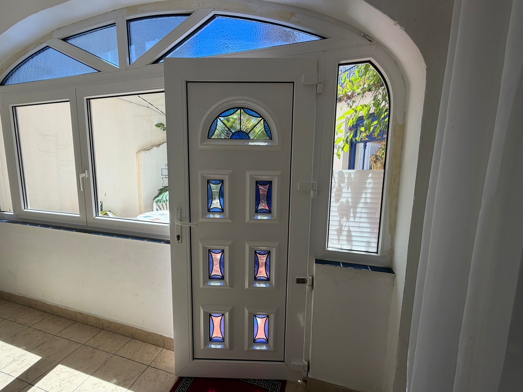 Eine weiße Tür mit Glasfenstern und einem kleinen Rundbogenfenster darüber.