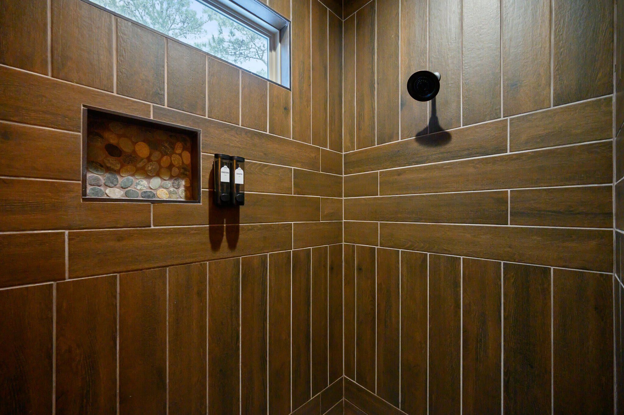 Rincón de una habitación con paneles de madera, un pequeño estante con piedras decorativas y un accesorio de luz negro fijado a la pared.