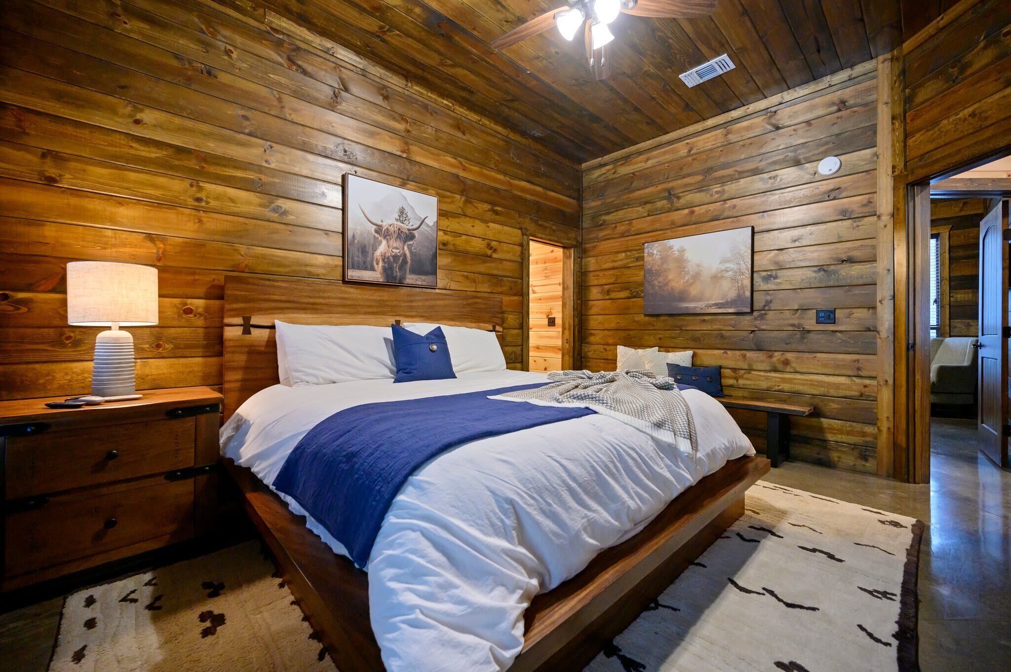 Ein Schlafzimmer in einer Holzhütte mit einem Bett, Nachttischen und Wandbildern.