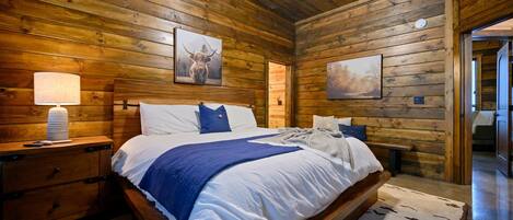 Ein Schlafzimmer in einer Holzhütte mit einem Bett, Nachttischen und Wandbildern.