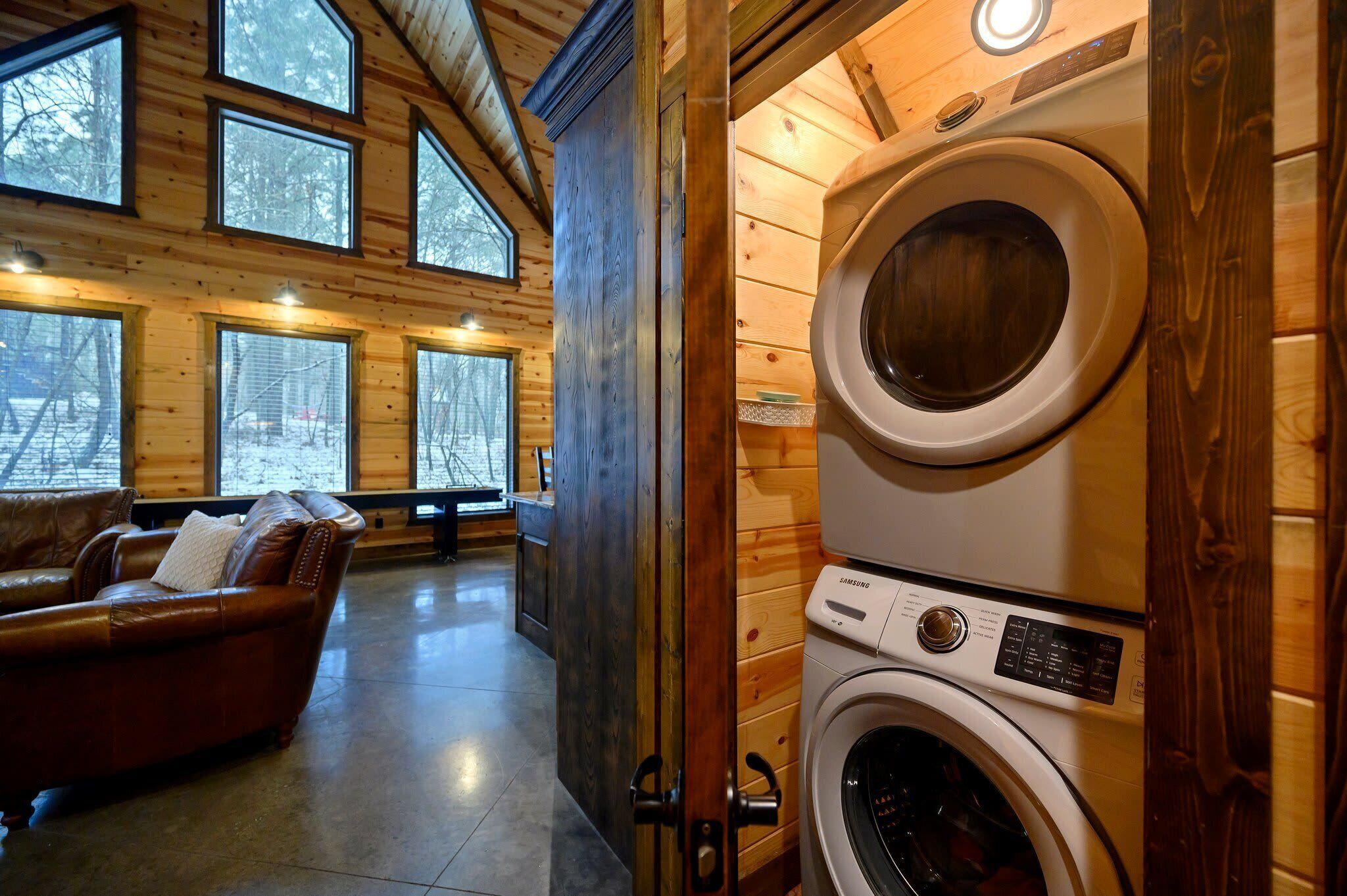 A cozy room with a large window, a washing machine, and a leather sofa.