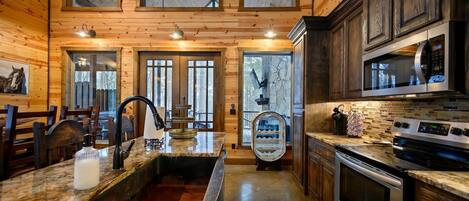 Una cocina amplia con encimeras de granito, electrodomésticos de acero inoxidable y muebles de madera.