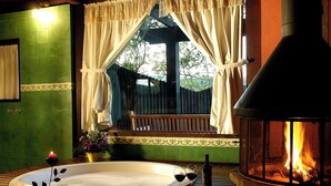 A hot tub with two rolled towels, a candle, and a bottle of wine. - Pousada Mauá Brasil (Resende)
