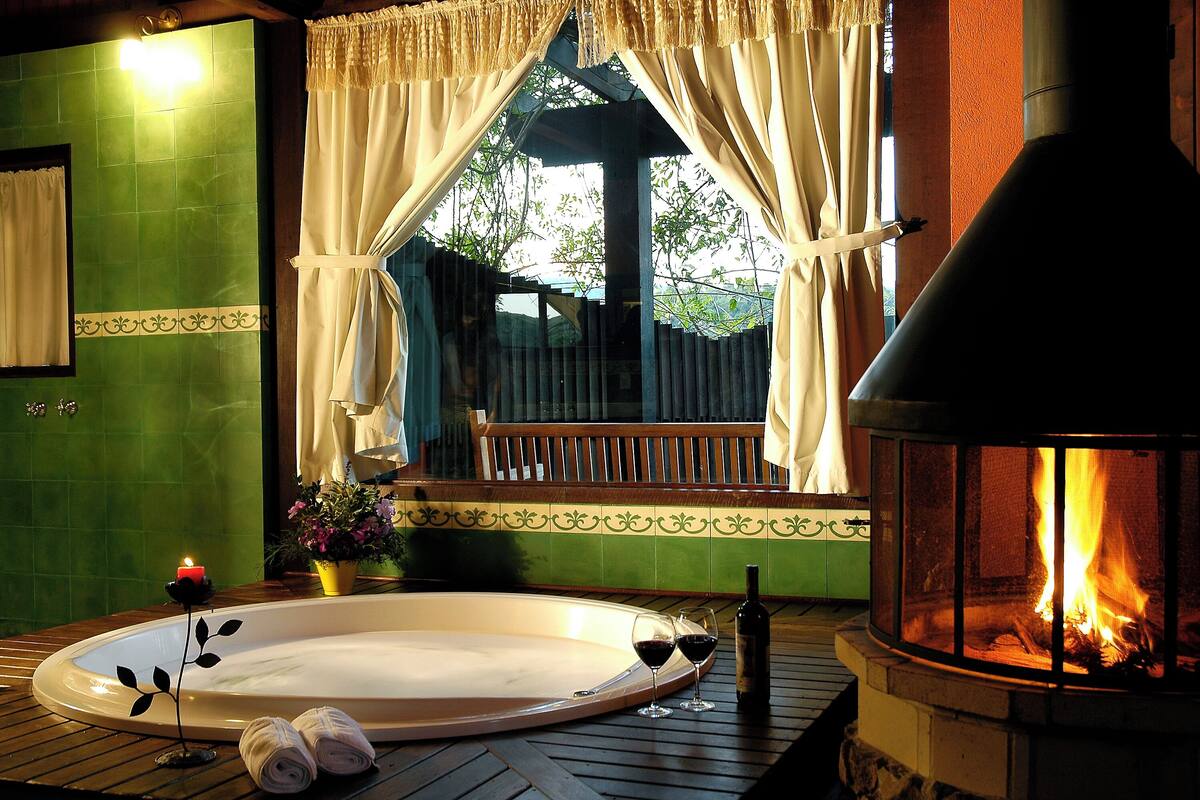 A hot tub with two rolled towels, a candle, and a bottle of wine.