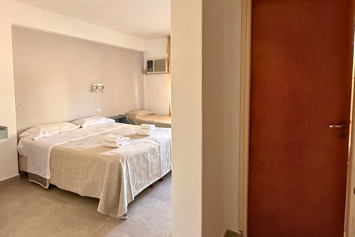 Ein Hotelzimmer mit zwei Betten, einer Holztür und einem Fliesenboden.