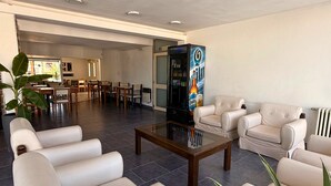 A spacious lobby with leather sofas, a coffee table, and a vending machine. - Hotel Montecarlo PSH (Villa Carlos Paz)