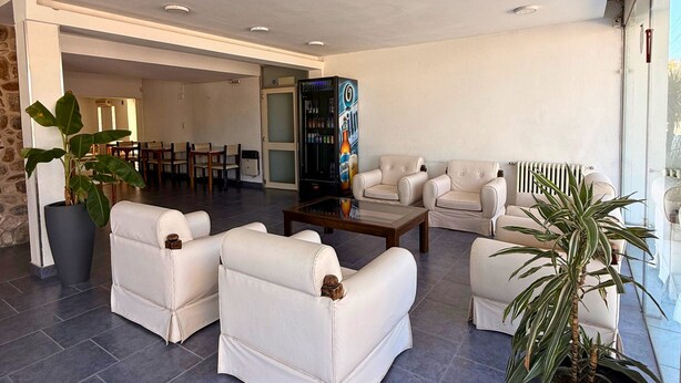 A spacious living area with modern white leather sofas, a coffee table, and large potted plants. - Hotel Montecarlo PSH (Villa Carlos Paz)