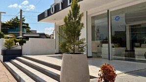 A hotel entrance with a sign, steps leading up to the entrance, and potted plants. - Hotel Montecarlo PSH (Villa Carlos Paz)