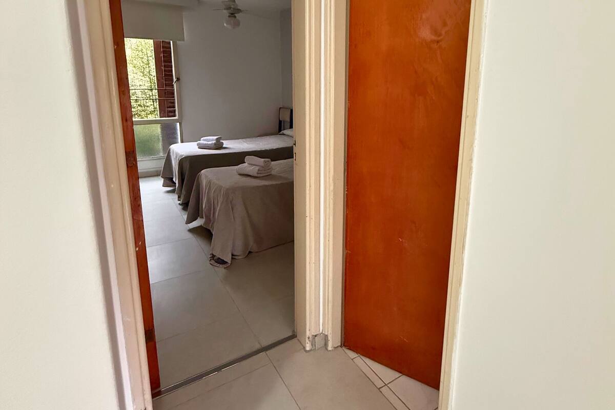 Ein Flur, der zu einem Zimmer mit einem Bett und einem Deckenventilator führt.