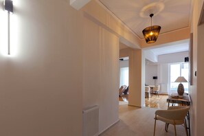 A spacious living area with a high ceiling, a modern chandelier, and a dining area with a table and chairs. - Phaedrus Living Metsovou Residence (Athens)