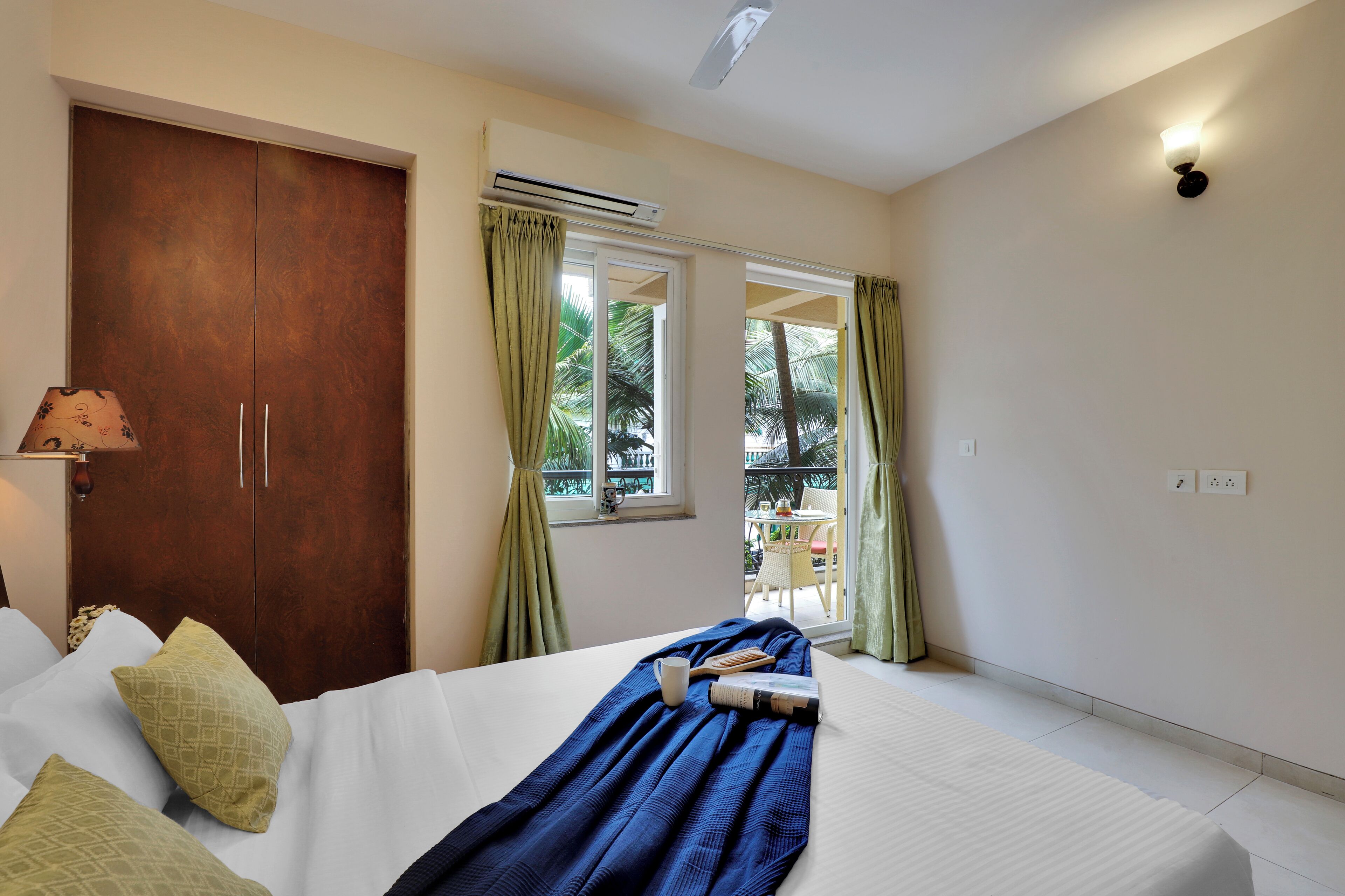 Habitación de hotel con cama, armario, ventana con cortinas y vistas al exterior.