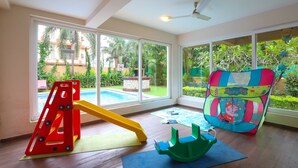 Un espace de jeux avec un toboggan, une tente colorée et une structure de jeux verte.