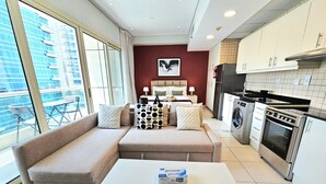Una sala de estar moderna con un sofá seccional color beige, una mesa de centro blanca y un ventanal que ofrece vistas a un edificio.