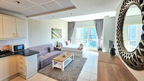 A modern apartment with a kitchen, living area, and a large window with a city view. - Sunrise Homes - Studio with Beautiful View next to JBR Walk and Beach (Dubai Marina)