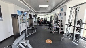 A gym with various exercise equipment, including weight machines and free weights. - Sunrise Homes - Studio with Beautiful View next to JBR Walk and Beach (Dubai Marina)