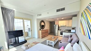 A modern hotel room with a large bed, a TV, a dining area, and a kitchen. - Sunrise Homes - Studio with Beautiful View next to JBR Walk and Beach (Dubai Marina)