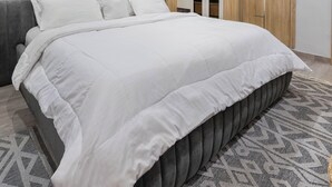 Een moderne slaapkamer met een groot bed, houten paneelwanden, een kledingkast en een kamerbreed tapijt.