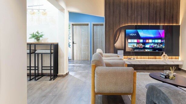Een moderne woonkamer met een grote flatscreen televisie, een houten salontafel en een bank.