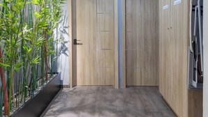 Een gang met houten deuren, een bamboe plant en een plafondlamp.