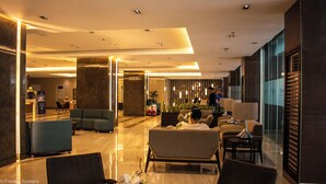Um lobby moderno com áreas de estar, balcão de recepção e divisória de vidro.