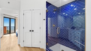 A modern bathroom with a blue-tiled shower enclosure and a white door. - 302C - 2 bedroom and 2 bath newly remodeled (ORANGE BEACH)