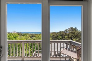 A balcony with a view of the ocean and greenery.