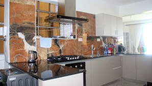 Eine moderne Küche mit schwarzem Arbeitsplatz, Edelstahlgeräten und einer Marmor-Spritzschutzwand.