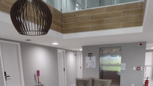 A modern living room with a grey sectional sofa, a grey armchair, and a small round table. There is a ceiling light fixture above the seating area.