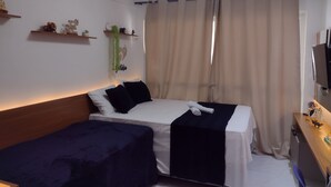 A hotel room with a bed, bedside table, and a TV.