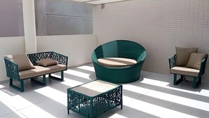 A modern outdoor seating area with two sofas and a round chair, a small table, and a tiled floor.