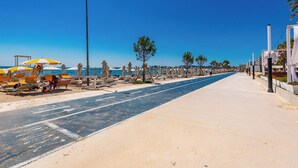 A beachside promenade with sun loungers, a clear blue sky, and a paved walkway. - Adriatic Seaview 1 by PS (kavaje)