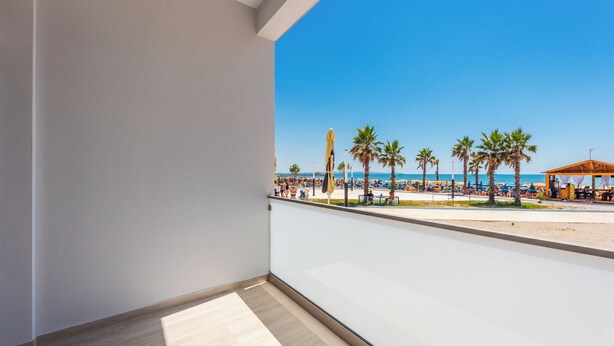 A balcony with a view of a beach, palm trees, and beach umbrellas. - Adriatic Seaview 1 by PS (kavaje)