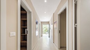 A hallway with a wooden floor, beige walls, and a door leading to a room. - Adriatic Seaview 1 by PS (kavaje)