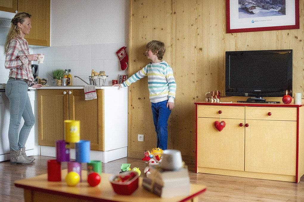 A kitchen with wooden cabinets, a television, and a table with colorful objects.