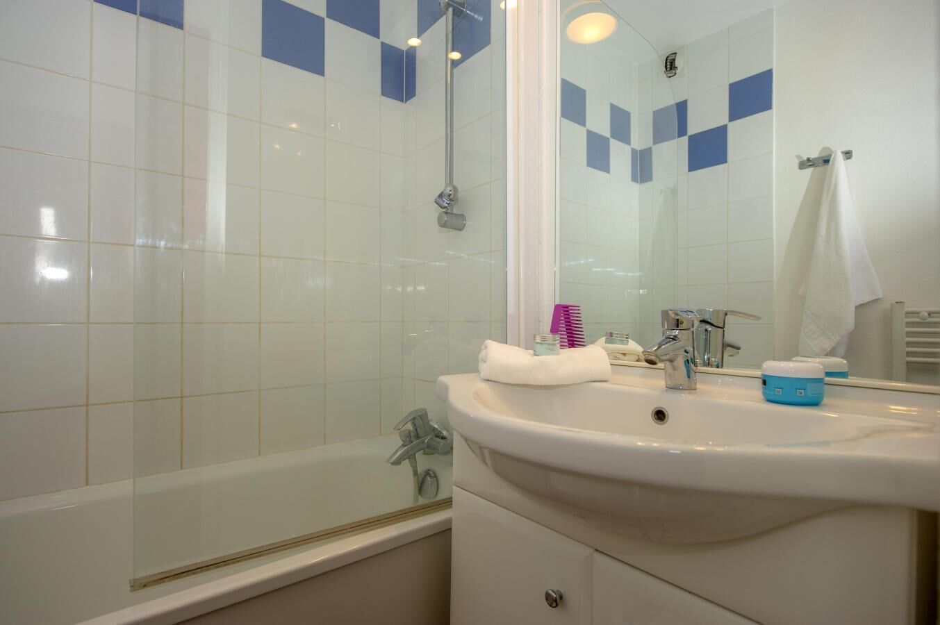 A bathroom with a bathtub, a sink, and a mirror.