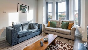 Ein Wohnzimmer mit zwei Sofas, einem Couchtisch und einem gerahmten Bild an der Wand.