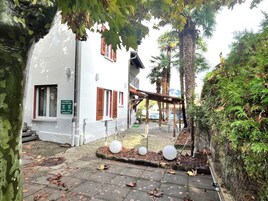 Un edificio con fachada blanca, contraventanas rojas y un letrero que indica que es una casa de huéspedes.