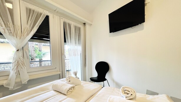 Une chambre d’hôtel avec deux lits, un téléviseur à écran plat fixé au mur et une chaise.