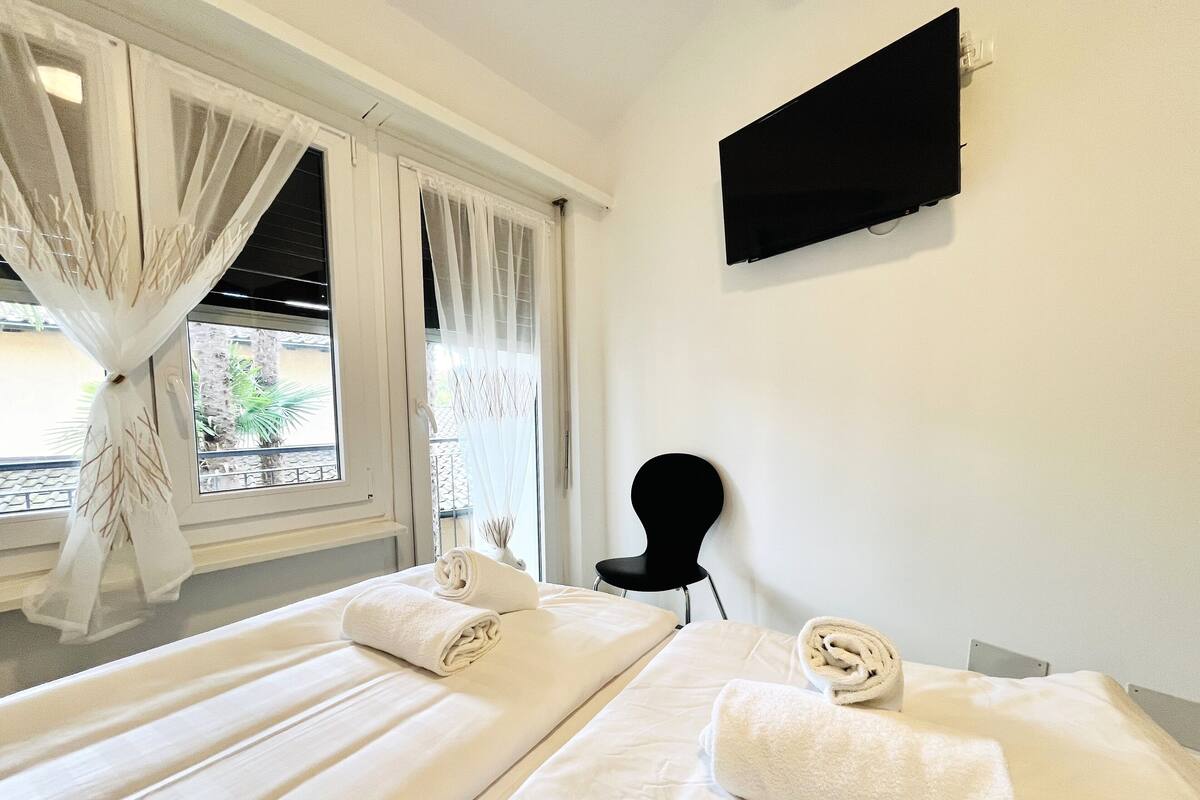 Una habitación de hotel con dos camas, un televisor de pantalla plana montado en la pared y una silla.