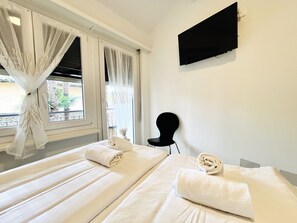 Una habitación de hotel con dos camas, un televisor de pantalla plana montado en la pared y una silla.