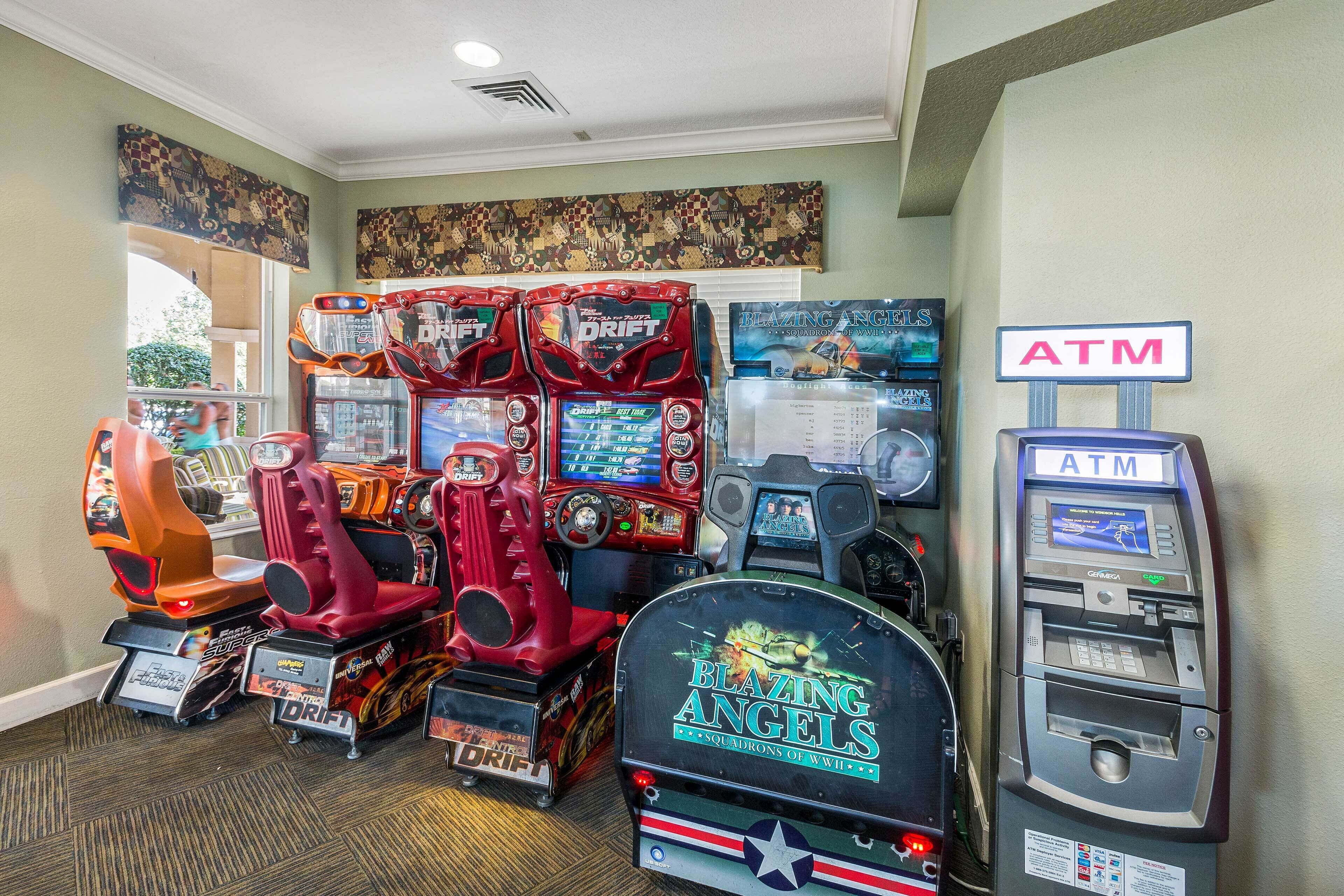 Een overdekte speelhal met verschillende spelautomaten, waaronder de spellen 'Blazing Angels' en 'Drift', en een geldautomaat.