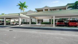A modern hotel with a covered parking area, multiple floors, and a green-tiled roof. - 5 Mi to Jetblue Park: Condo w/ Pool & Pickleball (Fort Myers)