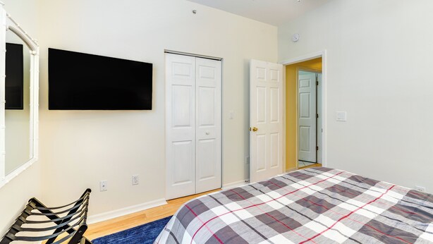 A bedroom with a bed, a TV mounted on the wall, and two doors. - 5 Mi to Jetblue Park: Condo w/ Pool & Pickleball (Fort Myers)