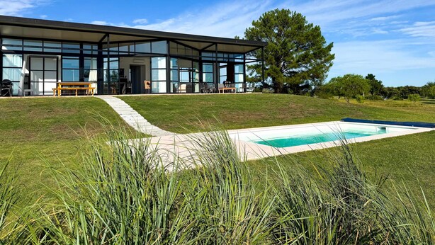 A modern house with large glass windows, a swimming pool, and a grassy lawn. - Panoramic by Carmelodays (Carmelo)