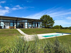 A modern house with large glass windows, a swimming pool, and a grassy lawn. - Panoramic by Carmelodays (Carmelo)